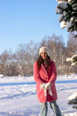 Fototapeta premium Young beautiful woman plays with snow in a winter park, throws it up and laughs.Winter concept.Selective focus,copy space.