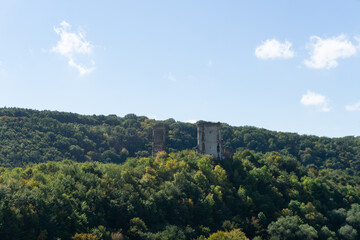 Ruins of the old castle on the hill hugged by autumn forest.