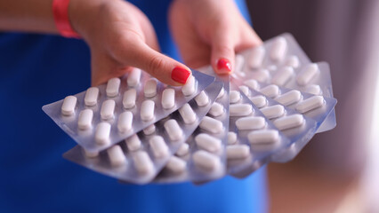 Woman hands hold lot of blisters with medical pills closeup