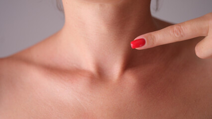 Woman manually checks thyroid gland in neck closeup
