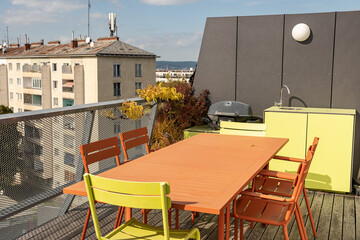 Green and terracotta outdoor furniture on a roof terrace in Vienna - dining table with outdoor kitchen and BBQ grill