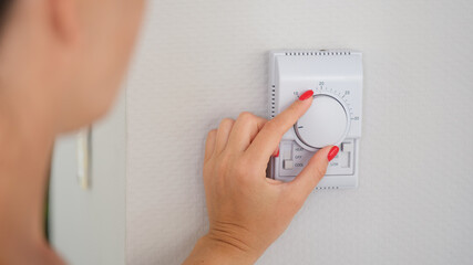 Hand adjusts button of the control unit of heating and cooling system of house closeup