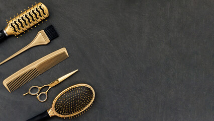 Hairdressing tools in gold on gray concrete background. Hair salon accessories, combs, scissors in...