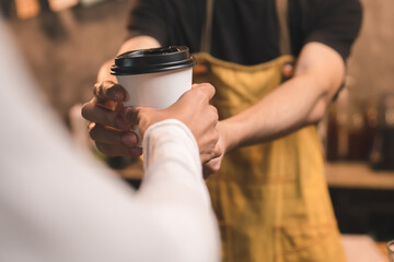 Close-up of hand Asian male barista serving coffee to customers in coffee shop Coffee business owner and coffee shop concept