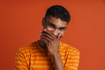 Portrait of young handsome african smiling man covering his mouth