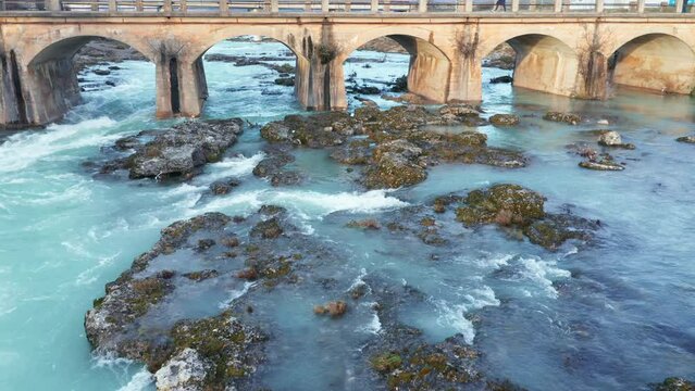 Blue river flowing under an arch bridge through beautiful rocky landscape. Aerial drone view of Cijevna (Cem, Cemi) stream in Montenegro, Europe.
