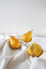 Ripe juicy pears on white color linen tablecloth.