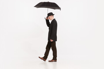 Portrait of stylish man in brown suit walking under umbrella isolated over white studio background