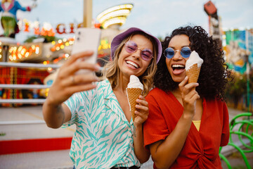 Young multiracial women taking selfie on cellphone in attraction park