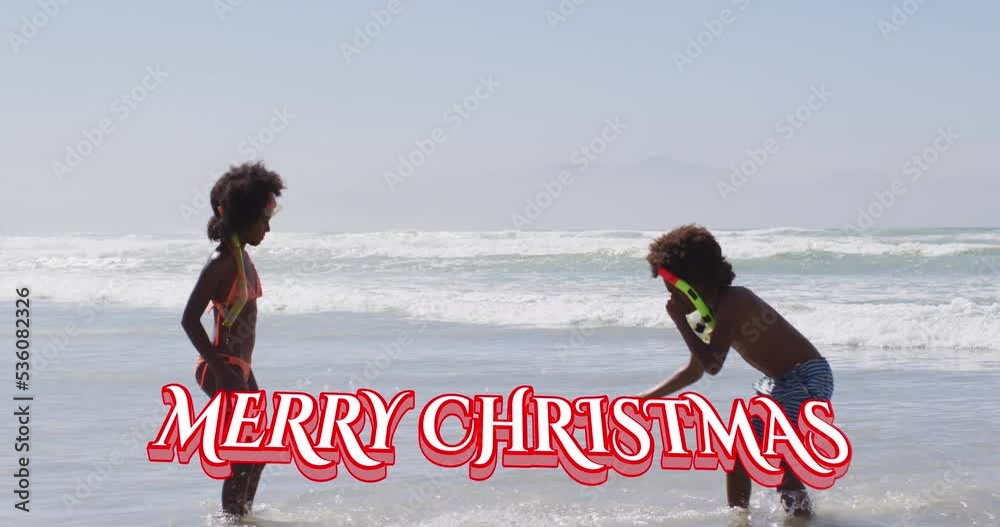 Sticker Animation of merry christmas over happy african american children playing on beach