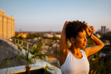 Young black woman in sportswear doing workout on rooftop outdoors