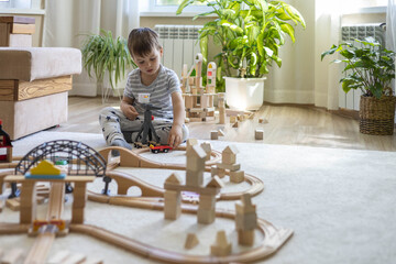Preschool baby boy playing wooden Montessori materials rainbow arch railways at childish room