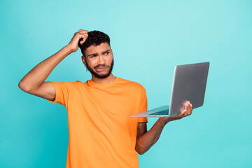 Portrait of clueless minded person arm scratch head use wireless netbook isolated on turquoise...