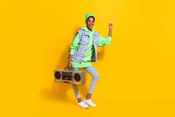Full size photo of carefree overjoyed girl hold vintage cassette recorder dancing isolated on yellow color background