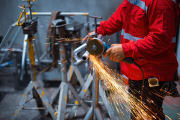 Worker using electric wheel spark grinding on metal steel is part of beam structure