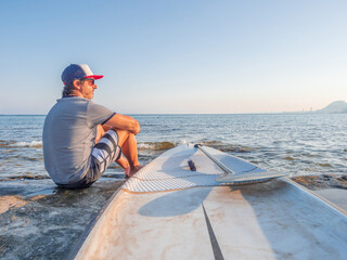 Mature man with surfboard on coast in water
