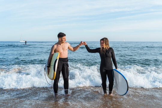 Young surfers giving high five near sea