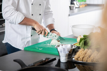 Professional chef demonstrating process of chopping onion at cooking workshop
