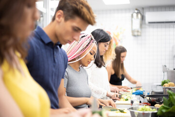 Multiracial people learning how to cut vegetables at cooking workshop