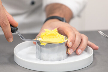 Unrecognizable chef spreading butter on baking form on plate