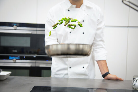 Professional chef with pan of asparagus cooking