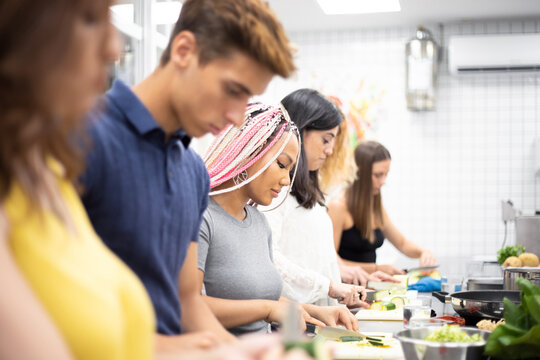 Multiracial people learning how to cut vegetables at cooking workshop