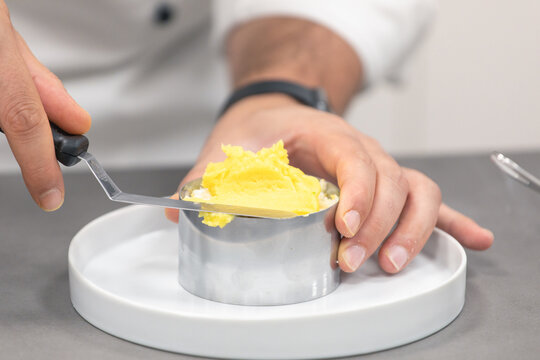 Unrecognizable chef spreading butter on baking form on plate