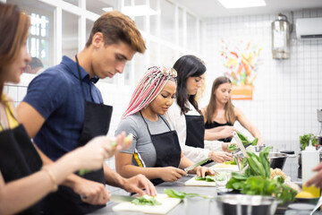 Multiracial people learning how to cut vegetables at cooking workshop