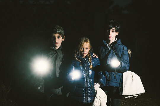 Children camping and playing with torch lantern in the dark