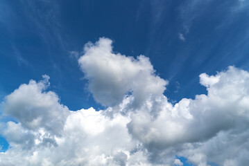 Blue sky with huge white clouds of bizarre shape.