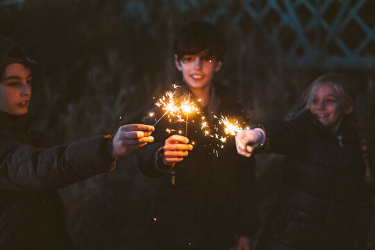 Group of young friends with sparkles on forest