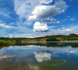 Fototapeta na wymiar Large white clouds over the lake water.