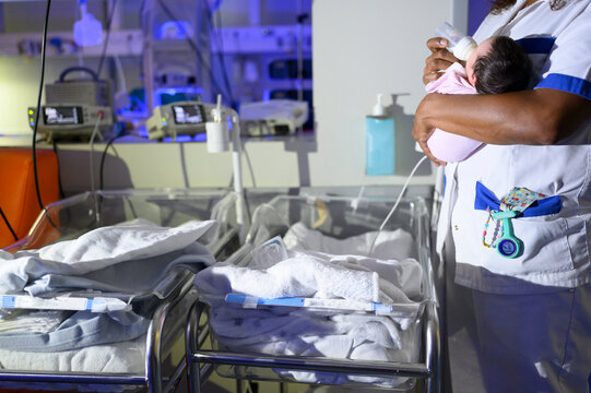 Nurse feeding newborn with milk bottle in maternity hospital