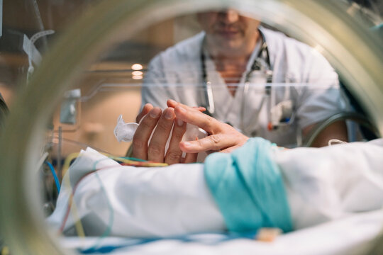 Doctor taking care of newborn baby in incubator