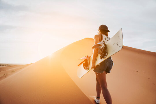 Young woman walking on sand ready for sandboarding