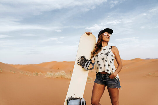 Young woman standing on sand ready for sandboarding