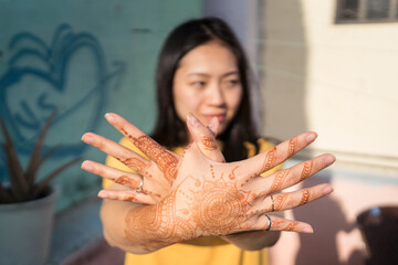 Asian woman with mehndi hands showing bird sign