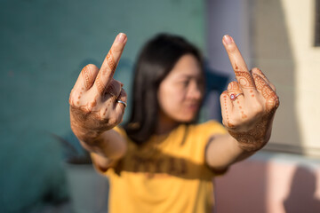 Asian woman showing middle fingers with mehndi