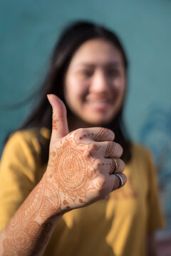 Content woman with mehndi hands showing thumb up