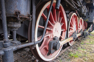 Drive transmission mechanism in a historic and damaged steam locomotive standing on a sidetrack. Rail.
