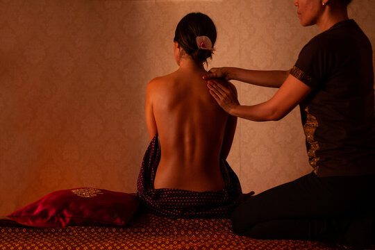 Thai female massagist giving a massage to a young woman