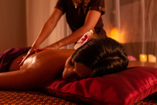 Thai female massagist giving a massage to a young woman