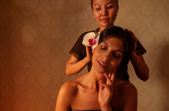 Thai female massagist giving a massage to a young woman