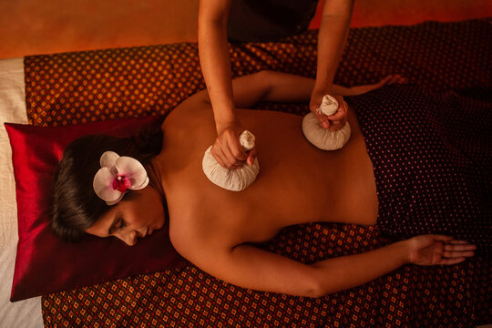 Thai female massagist giving a massage to a young woman