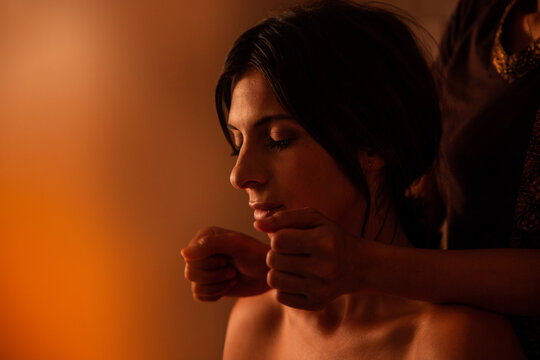 Thai female massagist giving a massage to a young woman