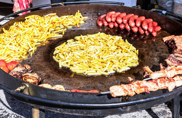 Appetizing grilled sausages and baked potatoes in a frying pan