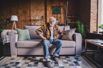 Obraz premium Photo of unhappy irritated man pensioner wear checkered shirt rising walking cane sitting sofa indoors house room