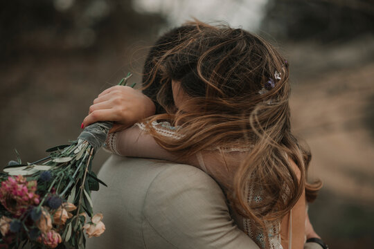 Man hugging with woman holding bouquet