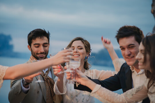 Young people in evening wear clanging glasses with drinks