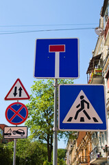 Group of traffic signs on the poles. Concept of road sign in big city. “Crosswalk” and “Dead...